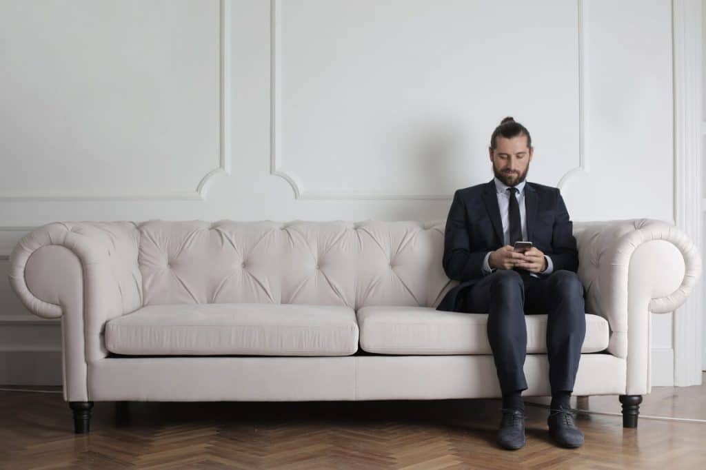 man working on smartphone on white couch